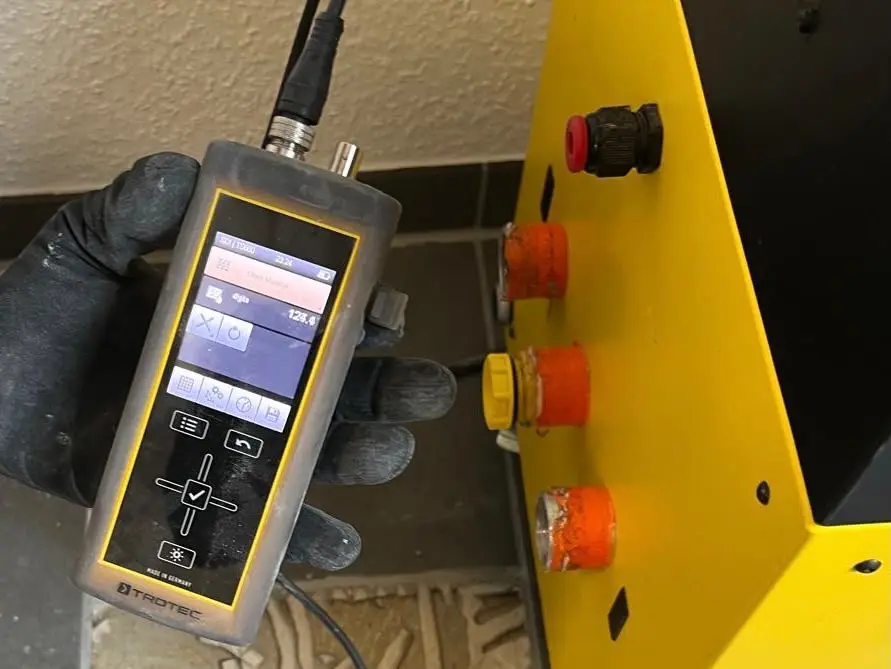Feuchtemessung mit Messgerät neben einem Trocknungsgerät bei der Bautrocknung
